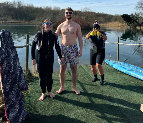 3 people in swimming clothes and wetsuits get ready to swim at Whitmore Lakes