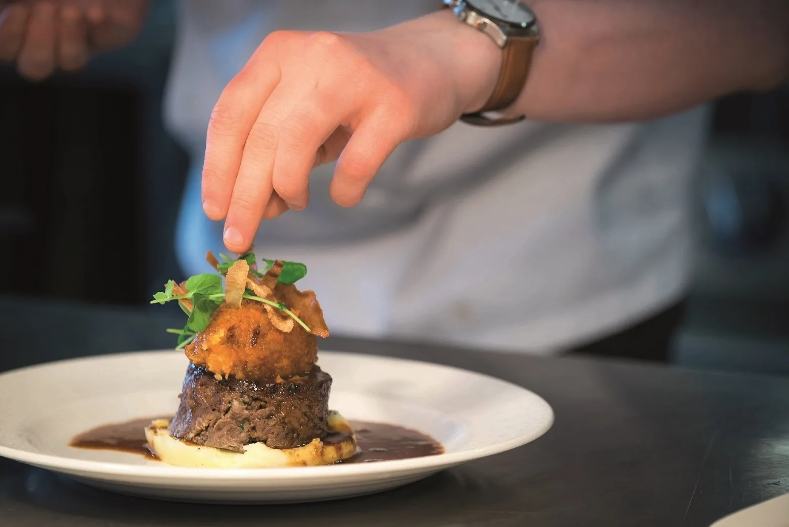 A chef adds a final garnish to some delicious food